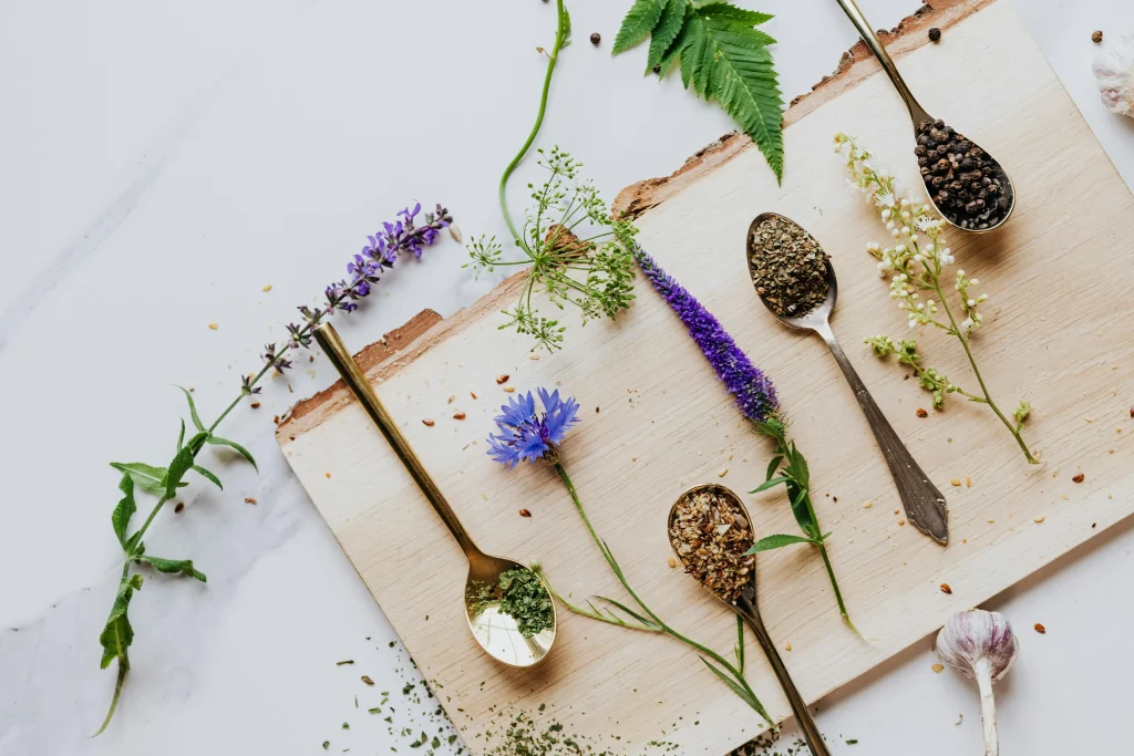 A wooden cutting board displaying various spoons alongside fresh herbs, creating a rustic kitchen scene